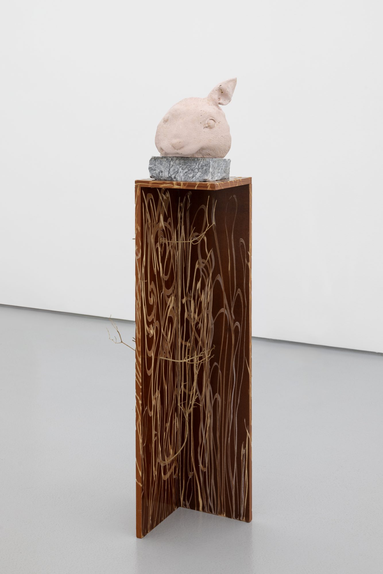 Susanne S. D. Themlitz, One-Ear Rabbit (Monument)/ Coelha-orelha (Monumento), 2025. Pigmented ceramic plaster, marble, veneered chipboard, tree branches. 143 x 50 x 27 cm.