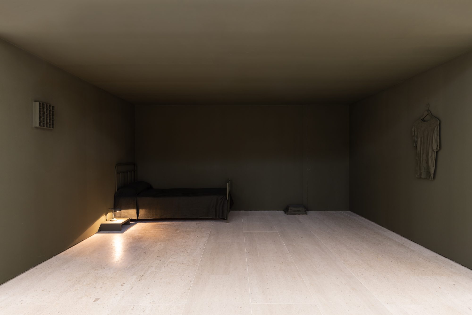 Carlos Bunga, The Place Where We Daily Abandon the World, 2021. Metal bed, mattress, pillow, fabric, lamp, bedside table, wall paint, painted cardboard structure, masking tape, glue paint-soaked t-shirt, hanger. Variable dimensions. Ed. 1
