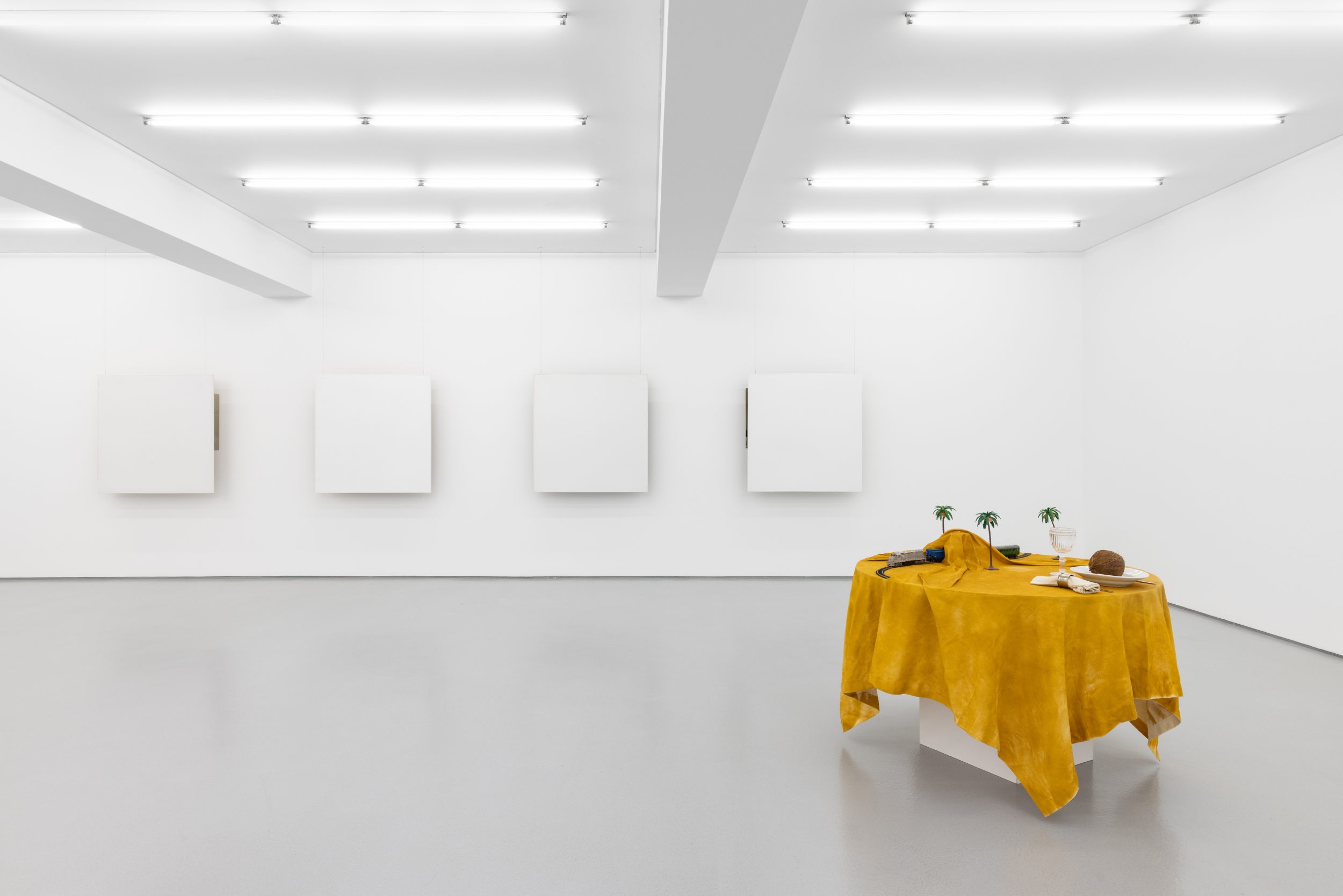 Ana Vieira, Mesa-Paisagem, 1973. Wooden table, fabric, spray paint on fabric, objects (plate, cutlery, napkin ring, napkin, plate, coconut, toy train and plastic palm trees). 94 x Ø110 cm
